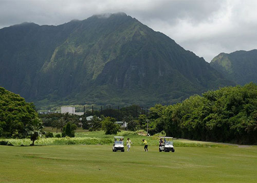 golfers teeing off with the mountains behind them